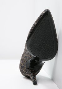 Chaussure à talon aiguille texturée noire et dorée avec un bout pointu et un talon stiletto élégant. La semelle en caoutchouc présente un motif de logo.