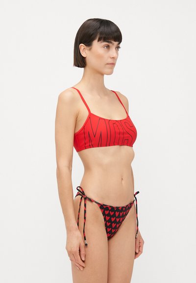 Sarkanais bikini top ar "MOSS" tekstu un melniem apakšiem, kuros ir sarkani sirds raksti. Regulējamas saites sānos. Mīksta, gluda auduma.