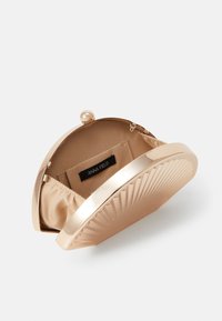 Gold metallic clutch purse with ribbed texture, rounded top, and a clasp closure. Interior features satin lining and a brand label.