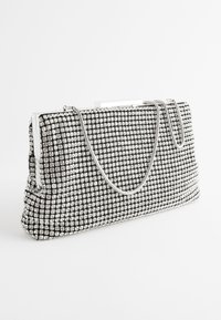 Zwarte rechthoekige clutch bedekt met zilveren strass-steentjes en een dunne zilveren kettingriem op een witte achtergrond.