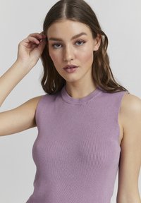 Lila ribbad stickad ärmlös topp med hög halsringning, som har en slät textur och tajt silhuett, med subtila detaljer vid kanterna.