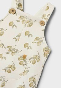 Rompertjes met bloemenpatroon in crème stof met groene bladeren. Voorzien van houten knopen en een voorzak met een merklabel.