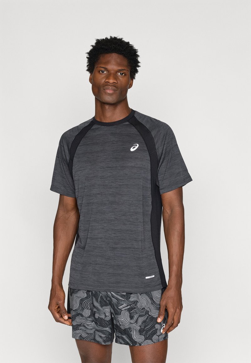 Μαύρο αθλητικό μπλουζάκι με υφή, κοντά μανίκια και πλέγμα στα πλάγια, σε συνδυασμό με μαύρες βερμούδες με σχέδια που περιλαμβάνουν κυματιστές γραμμές.