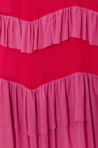 Röd tyg med lager av rosa volanger, med en slät textur. Volangerna är gathered och skapar ett vågigt mönster.