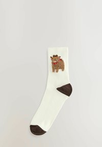Chaussettes blanches avec un talon et un orteil marron, présentant un motif d'animal en peluche marron portant un chapeau de cowboy et un collier rouge.