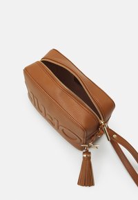 Borsa in pelle color cuoio con superficie texturizzata, chiusura a doppia zip e un tassello decorativo. Presenta una marcatura a caldo su un lato.