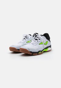 Scarpe da ginnastica bianche con dettagli neri e un logo verde neon, caratterizzate da una tomaia in mesh testurizzato e una suola in gomma beige con battistrada pattern.