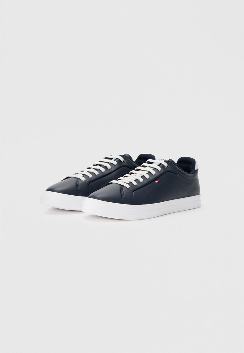 Navy blue leather sneakers with white soles and laces. Features a smooth texture and minimalistic design, including subtle branding on the side.