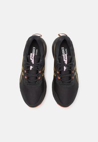 Black athletic shoes with orange accents, mesh upper, and padded tongue. Features contrasting yellow stripes and black laces.