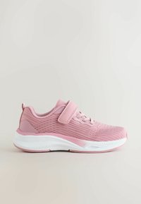 Baskets de sport roses avec dessus texturé, bride auto-agrippante, lacets et semelle blanche épaisse sur fond neutre.