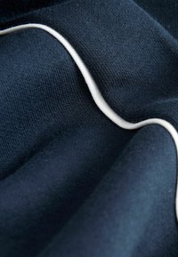Merkin kangas, jossa on sileä pinta ja vastakkaista valkoista reunapiperrystä, esittäen taittuneen ulkonäön.