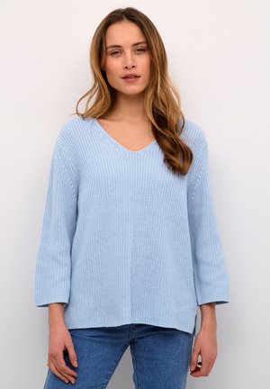 Lysblå strikket trøje med V-hals, trekvartærmer, struktureret stof og en let oversized pasform, bæret med blå jeans.