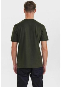 T-shirt a maniche corte di un verde oliva scuro realizzato in cotone; design semplice con collo rotondo e orlo dritto; senza motivi o grafiche visibili.