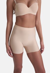 Beige sömlösa shapewear-shorts med hög midja, slät textur och längd till mitten av låret. Har ett subtilt, elastiskt midjeband.