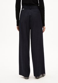 Navy wijde broek met witte streepjes, voorzien van een hoge tailleband en een achterzak. Gladde stof, op maat gemaakt ontwerp en subtiele glans.