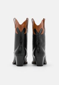 Stivali western in pelle nera con effetto cocco, con un accento marrone nella parte superiore. Presentano ritagli appuntiti e un tacco impilato.
