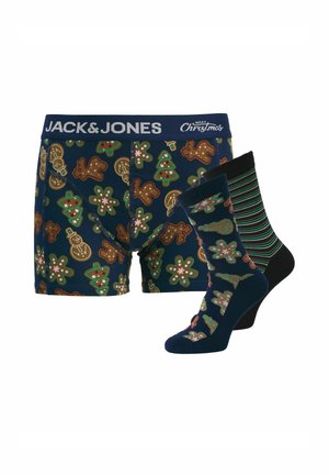 Marineblauwe boxershorts met peperkoek- en kerstboompatronen, gecombineerd met één gestreepte sok en één sok die past bij het ontwerp van de boxershorts.