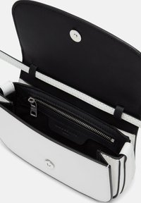 Weiße Lederhandtasche mit schwarzem Innenraum, verfügt über einen Magnetverschluss, ein Reißverschlussfach und dekorative Nähte.