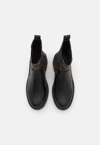 Botas de cuero negras hasta el tobillo con laterales elásticos, que presentan un panel texturizado marrón. Punta redondeada y suela de goma para mayor tracción.