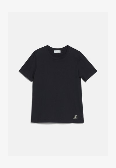 T-shirt noir à manches courtes et col rond avec un petit logo blanc brodé près de l'ourlet inférieur sur un fond clair uni.