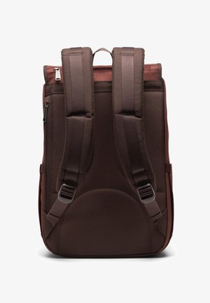 Ruskea reppu, jossa on pehmustetut ja säädettävät olkahihnat, lenkkikahva ja sivu-zip-tasku; sileä rakenne ja suorakulmainen muoto.