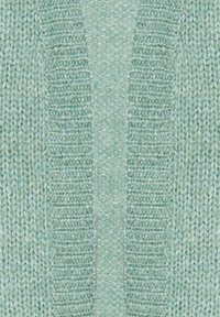 Tessuto lavorato a maglia verde chiaro con una texture a coste lungo i bordi e un pannello centrale liscio. Modello di punto uniforme in tutto il tessuto.
