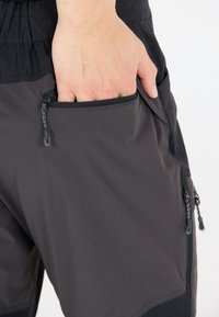 Grå shorts med en ficka med dragkedja och svart kant, elastisk midja och integrerade dragkedjestaplar för enkel åtkomst.