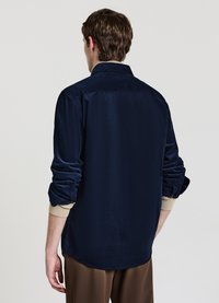 Camicia in velluto blu navy con vestibilità comoda, caratterizzata da maniche lunghe, polsini arrotolati con accenti beige e colletto appuntito.