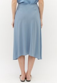 Jupe midi bleu clair en tissu doux, avec une silhouette fluide, un ourlet asymétrique et une texture lisse. Design minimaliste.