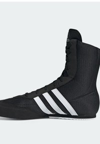 Black high-top Adidas boxing shoe with white stripes and laces, textured fabric, and rubber sole, shown from the side.