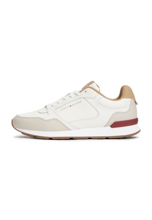 Baskets blanches et beiges Tommy Hilfiger avec des accents beige clair, lacets à l'avant et détail du logo rouge sur le talon et le panneau latéral.