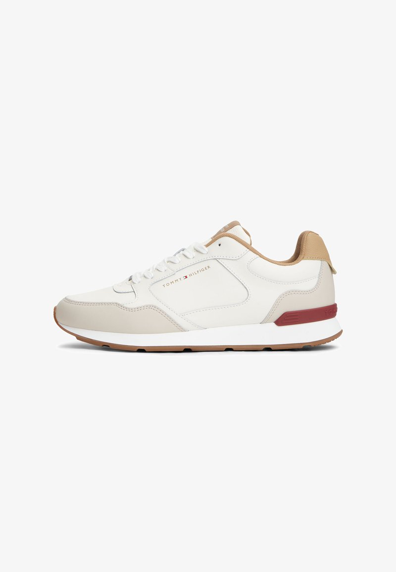 Baskets blanches et beiges Tommy Hilfiger avec des accents beige clair, lacets à l'avant et détail du logo rouge sur le talon et le panneau latéral.