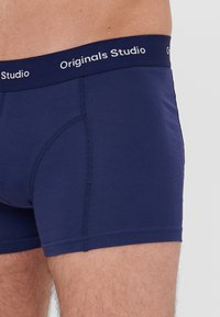 Navy blauwe boxershort van zacht, rekbaar materiaal. Voorzien van een gestikte tailleband met het "Originals Studio" logo in het wit. Aansluitend ontwerp.