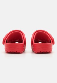 Red rubber clogs with an open back, textured interior, and a patterned sole. Features a side strap for a secure fit.