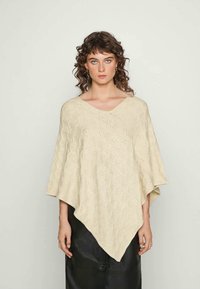 Poncho de malha de cor creme com decote em V, apresentando um padrão de rendado e uma forma solta e fluida. Textura suave, caimento elegante.