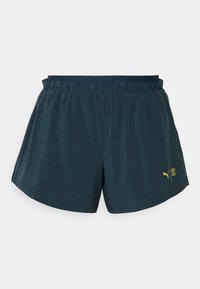 Mörk teal träningsshorts med elastisk midjeband, slät textur och gult Puma-logotyp på nedre högra sidan. Klassisk shortsdesign.