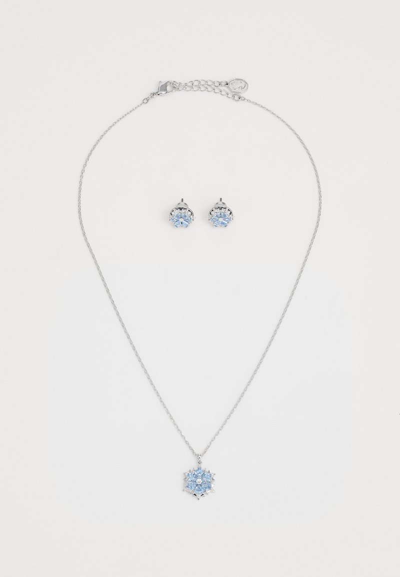 Silbernes Schmuckset mit einer Halskette mit einem Schneeflocken-Anhänger und passenden Ohrsteckern, beide verziert mit hellblauen Edelsteinen.