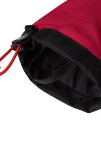 Crvena i crna platnena torbica s vezicom za zatvaranje, glatkom vanjštinom, teksturiranom crnom bazom i malom petljom za nošenje.