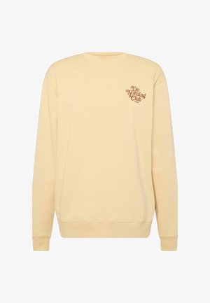 Sárga kereknyakú pulóver, bordás ujjak és aljjal. A bal mellen "Do Nothing Club" felirat van nyomva barna színben. Puha pamut keverék anyag.