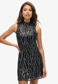 Robe noire sans manches avec un col haut, ornée de sequins dans un motif en vagues, présentant un corsage ajusté et une jupe évasée.