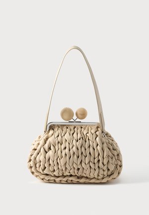 Sac à main beige tissé avec une texture tressée épaisse, une seule bandoulière et une fermeture métallique surmontée de deux sphères beiges rondes.