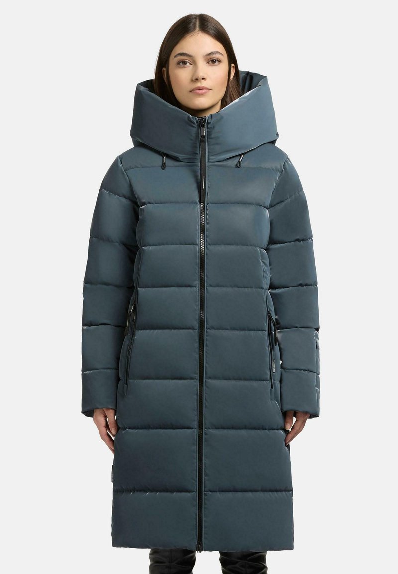 Cappotto imbottito lungo di un verde bluastro scuro con colletto alto, dotato di chiusura con zip, grande cappuccio e tasche laterali. Design imbottito con una consistenza liscia.