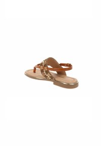 Sandalo flat con cinturini in finta pelle marrone, caratterizzato da accenti intrecciati e un bordo metallico sulla suola. Sottopiede liscio con design minimalista.