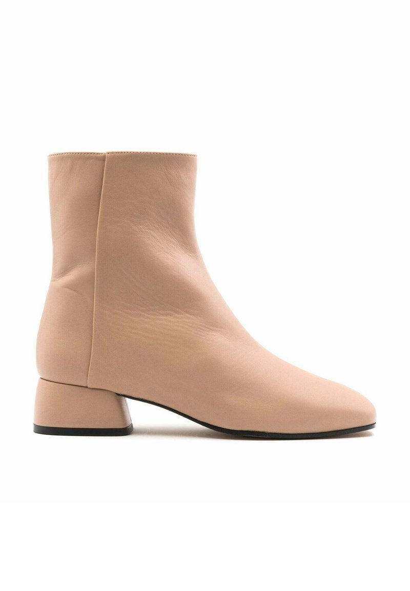 Botas de tobillo rosa claro hechas de cuero suave, con un tacón cubano cuadrado y una punta afilada, con costuras mínimas y un diseño elegante.