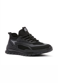 Czarne sportowe sneakersy z teksturowanej siateczki, z wyściółką w kołnierzu i gumową podeszwą. Wyposażone w akcenty odblaskowe i rzeźbiony design.