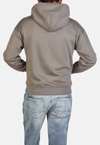 Lichtgrijze hoodie met een ruime capuchon, ribbelmanchetten en onderrand, gedragen over vervaagde blauwe jeans, die een zachte, gladde stofstructuur toont.