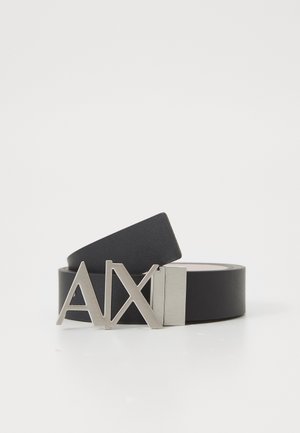 Schwarzer Leder-Gürtel mit flachem Design, ausgestattet mit einer silbernen Metallschnalle, auf der die Buchstaben "AX" deutlich sichtbar sind. Glatte Oberfläche.