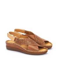 Sandalias de cuña en cuero marrón con diseño floral perforado, tiras cruzadas y detalle trenzado en el borde.
