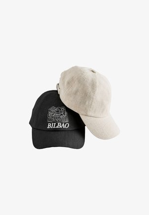 Deux casquettes de baseball en lin, une beige unie et une noire avec une broderie florale blanche et le mot "BILBAO" à l'avant.