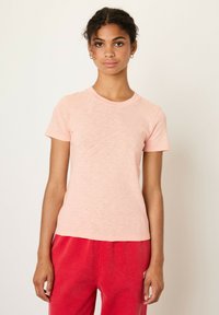 Svetlo roza kratkopr sleeves t-shirt iz mehkega, teksturiranega blaga s klasičnim okroglim ovratnikom. Ujemajoče se rdeče trenirke.